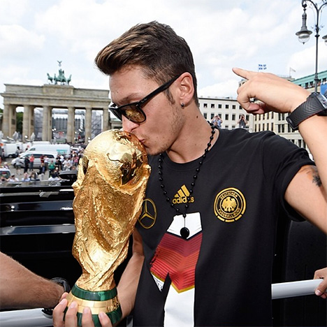 Mesut Ozil is kissing the World Cup trophy