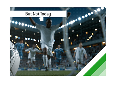 Dramatic football scene showing a late goal celebration as players race away from the net.
