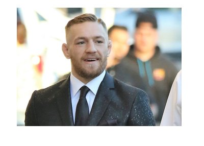 Conor McGregor strolling down the street in a fancy suit.  Big smile on his face.