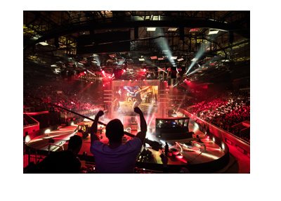 Esports event held in Russia.  Man celebratin in front of a large crowd looking at the big screen.