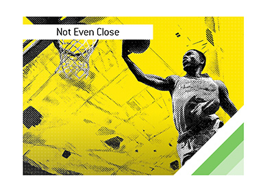 College basketball player soaring for an uncontested dunk with trailing defenders far behind.