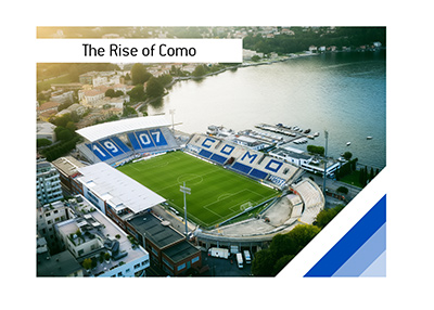 Aerial illustration of Como stadium - Stadio Giuseppe Sinigaglia beside Lake Como, with blue-and-white stands and hillside buildings in warm sunlight.