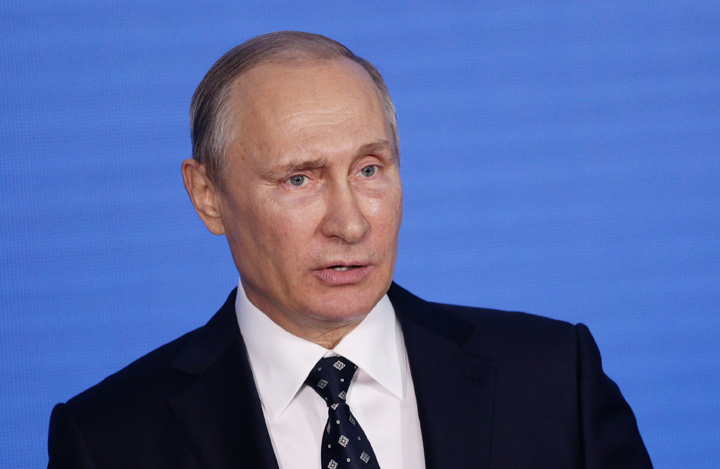 Russian president, Vladimir Putin, photographed during a speach. Blue background is behind him.