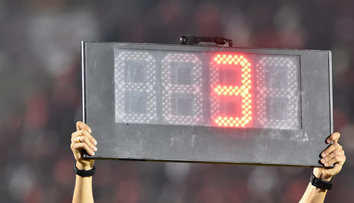 The referee is holding up a sign showing the minutes of extra time to be added at the end of the soccer match.  This time is also called injury / stoppage time.