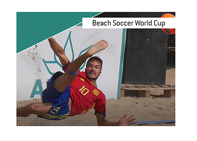 A scene from the Beach Soccer World Cup qualifying match featuring a number 10 Spain player scizzor kicking the ball.
